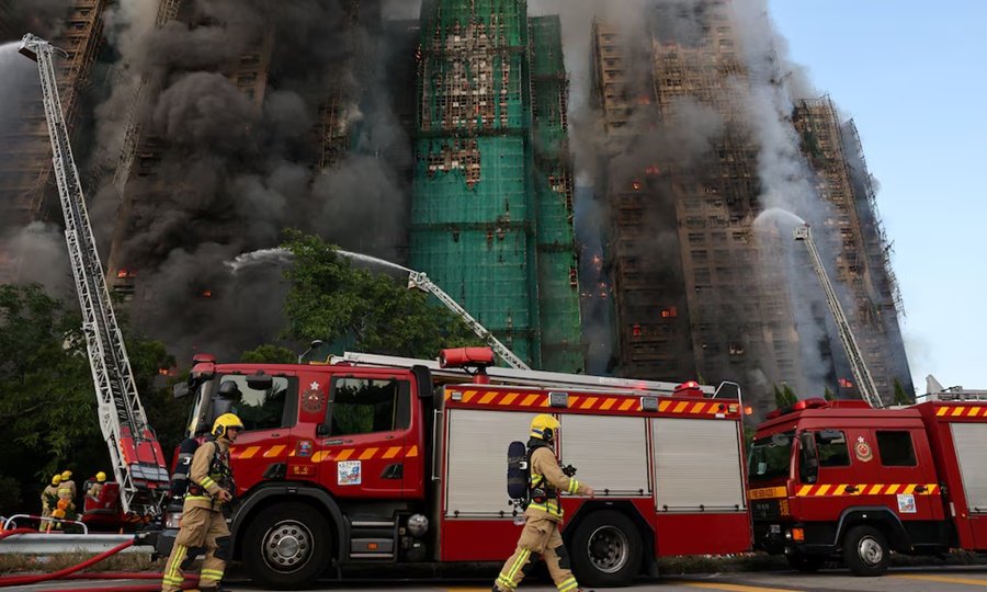 Bomberos trabajan entre el humo y los restos del andamiaje colapsado en el complejo afectado de Tai Po.
