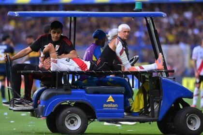 Maxi Meza es retirado del campo con visibles gestos de dolor tras sufrir la lesión en el Superclásico ante Boca.