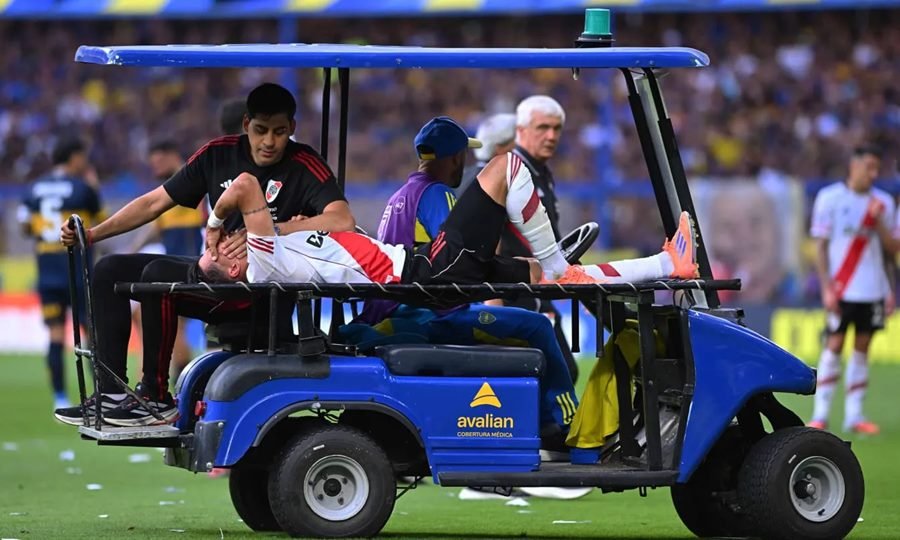 Maxi Meza es retirado del campo con visibles gestos de dolor tras sufrir la lesión en el Superclásico ante Boca.