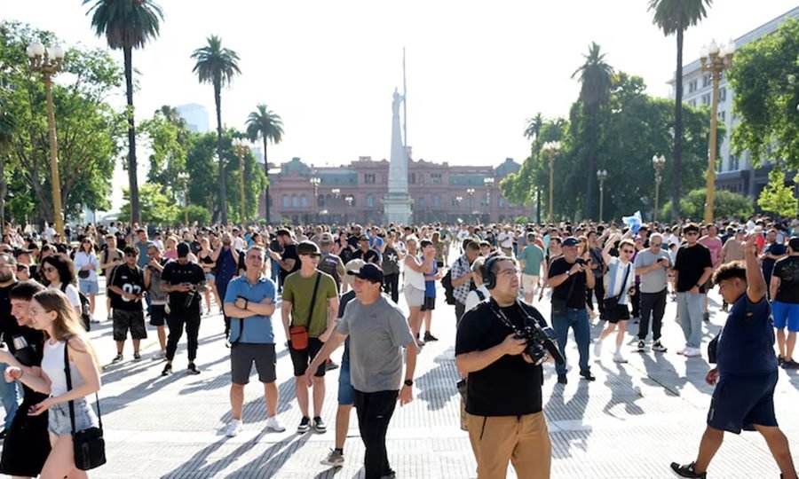 Asistentes observando el cielo desde la Plaza de Mayo en un evento público.