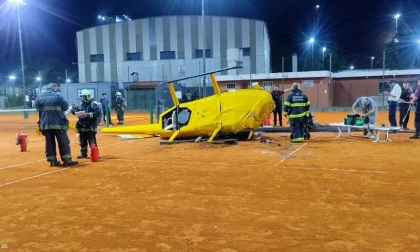 Bomberos y personal de emergencia trabajan sobre la cancha de tenis instantes después de la caída del helicóptero.