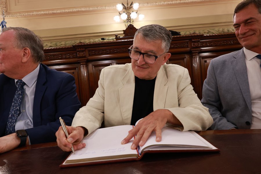 José D’Abarno firma el Libro de Honor durante el acto de reconocimiento en la Cámara de Senadores.