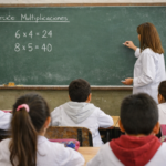 Docente dicta clase frente al pizarrón mientras alumnos asisten a una escuela pública de la provincia de Santa Fe. Imagen ilustrativa