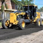 Trabajos de mejora vial con maquinaria municipal en calles urbanas.