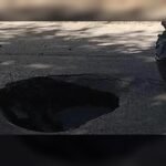 Socavón de gran tamaño en una calle urbana tras el hundimiento del pavimento.