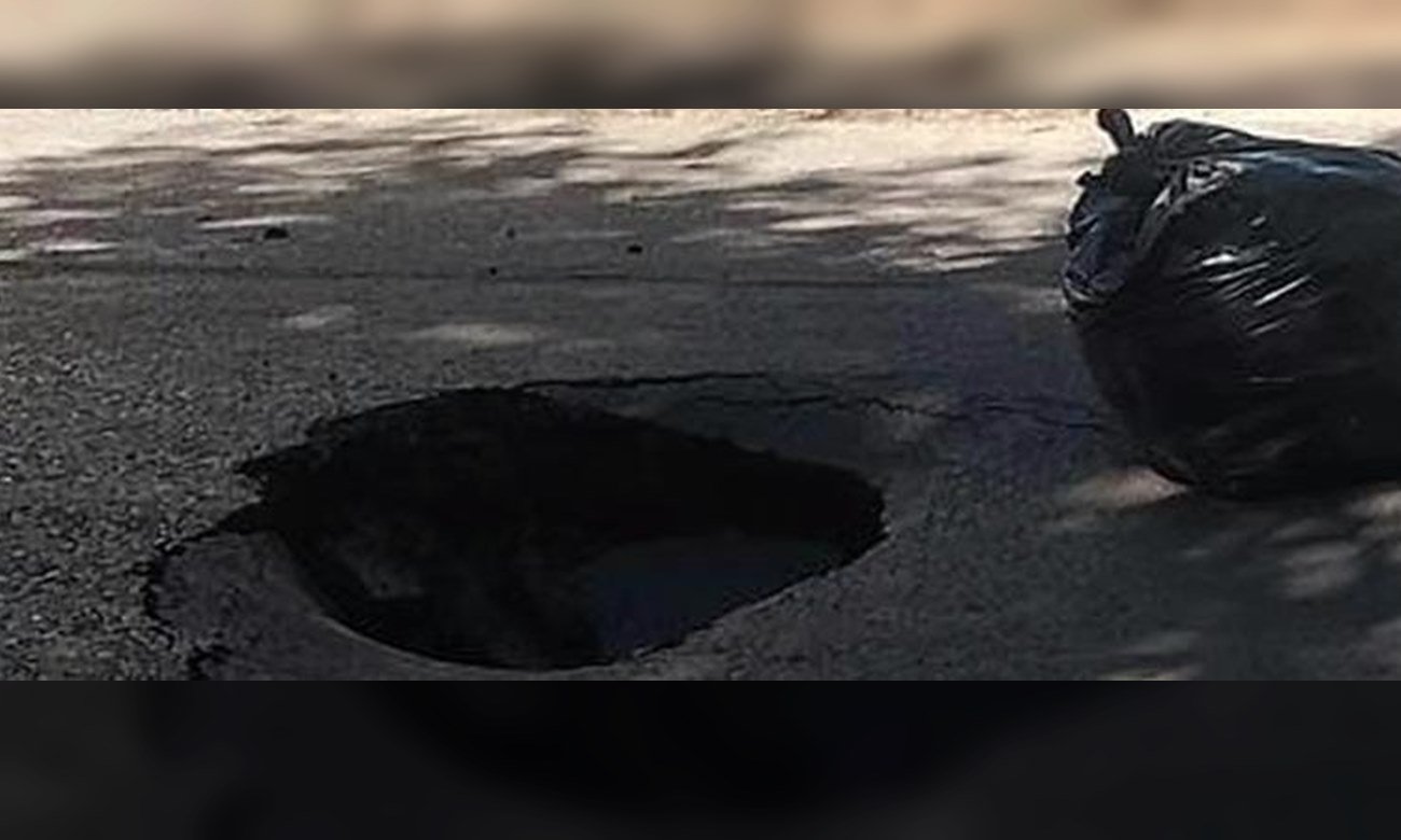 Socavón de gran tamaño en una calle urbana tras el hundimiento del pavimento.