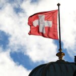 Vista de la bandera de Suiza ondeando, símbolo histórico de neutralidad y soberanía nacional.