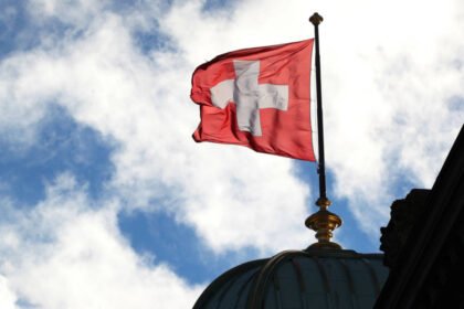 Vista de la bandera de Suiza ondeando, símbolo histórico de neutralidad y soberanía nacional.