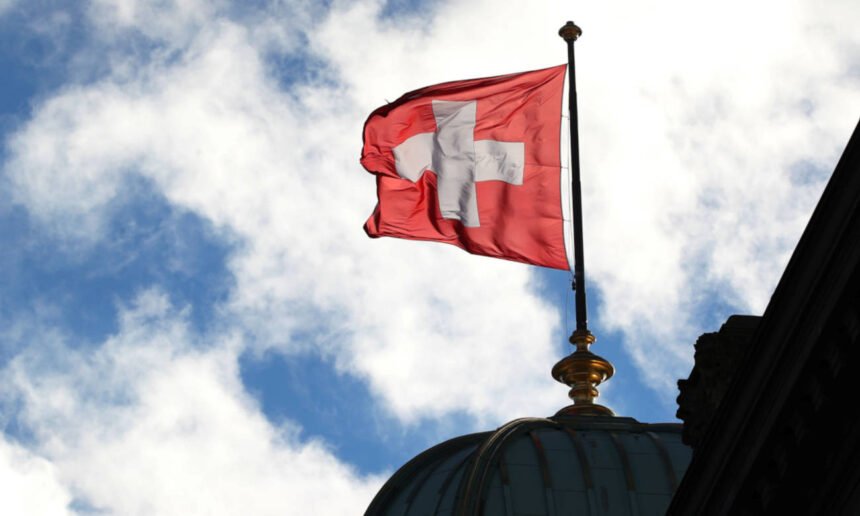 Vista de la bandera de Suiza ondeando, símbolo histórico de neutralidad y soberanía nacional.