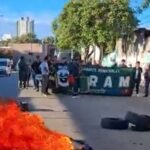 Manifestación de trabajadores municipales con corte de tránsito y quema de cubiertas en una avenida urbana.