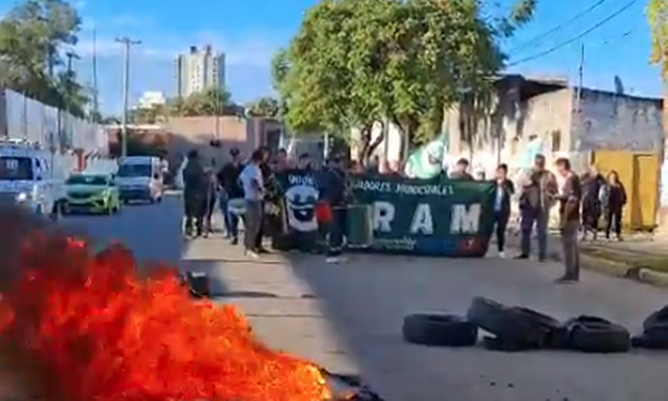 Manifestación de trabajadores municipales con corte de tránsito y quema de cubiertas en una avenida urbana.