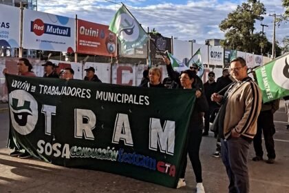 Protesta de trabajadores municipales con corte de tránsito y reclamos laborales en una avenida urbana.