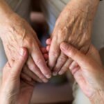 Cuidador asiste a una persona mayor en un entorno domiciliario. Imagen ilustrativa.