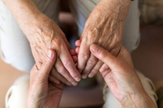 Cuidador asiste a una persona mayor en un entorno domiciliario. Imagen ilustrativa.