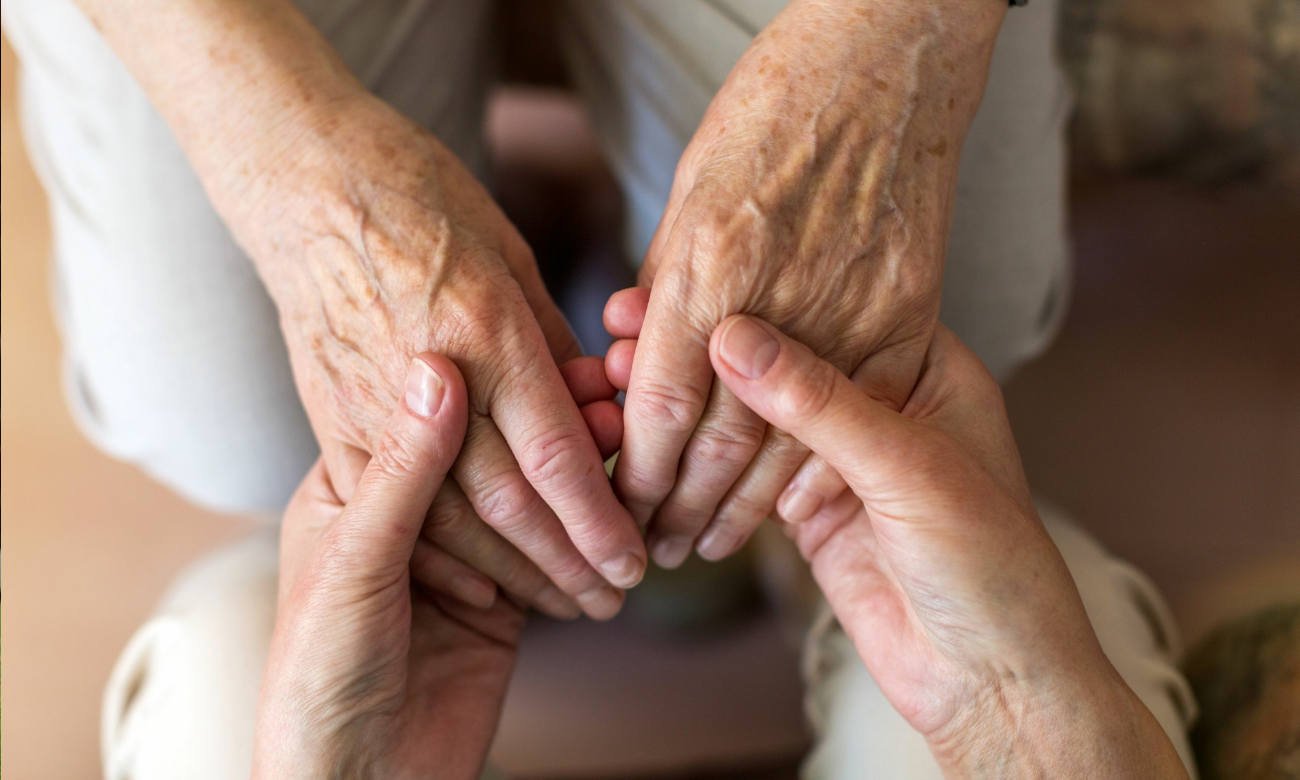 Cuidador asiste a una persona mayor en un entorno domiciliario. Imagen ilustrativa.