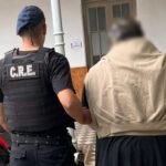 Hombre de 66 años detenido y trasladado a sede policial en la ciudad de Santa Fe, escoltado por efectivos tras ser acusado de amenazar a su familia.