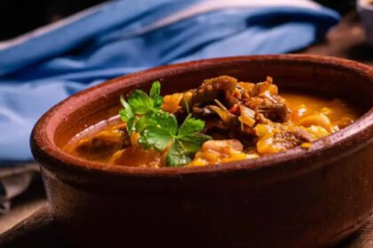 Plato de locro argentino tradicional preparado con carnes, maíz blanco, porotos y zapallo.