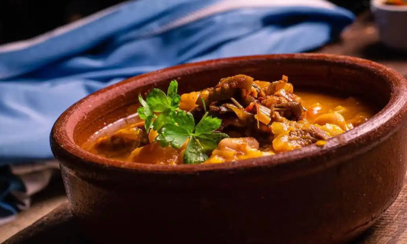 Plato de locro argentino tradicional preparado con carnes, maíz blanco, porotos y zapallo.