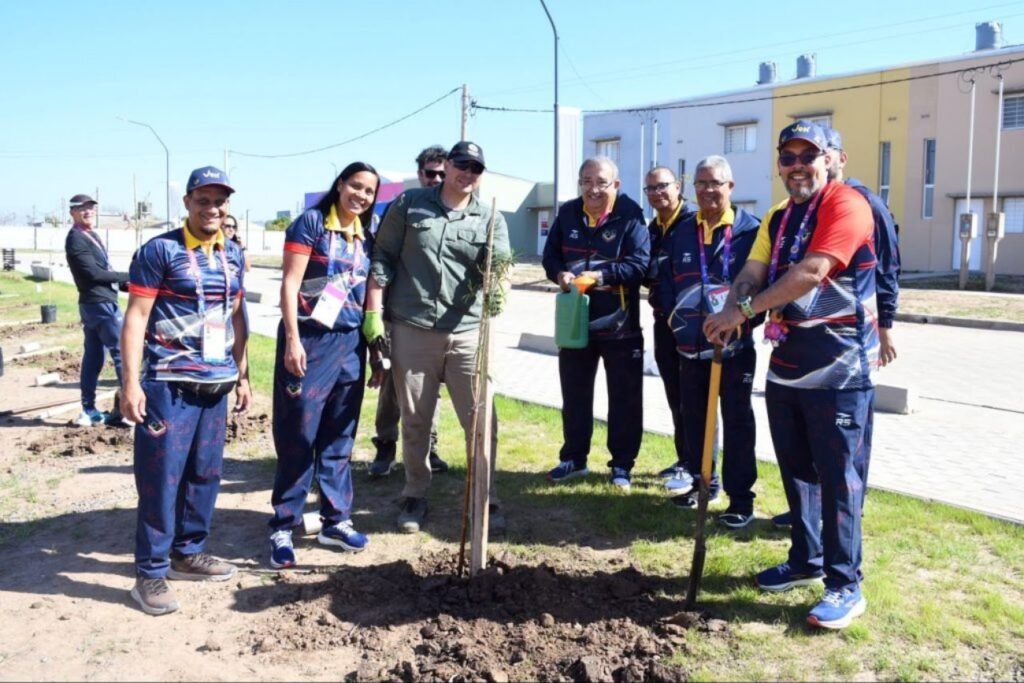 Deportistas y representantes de delegaciones participan de una jornada de plantación de árboles en la ciudad de Santa Fe.