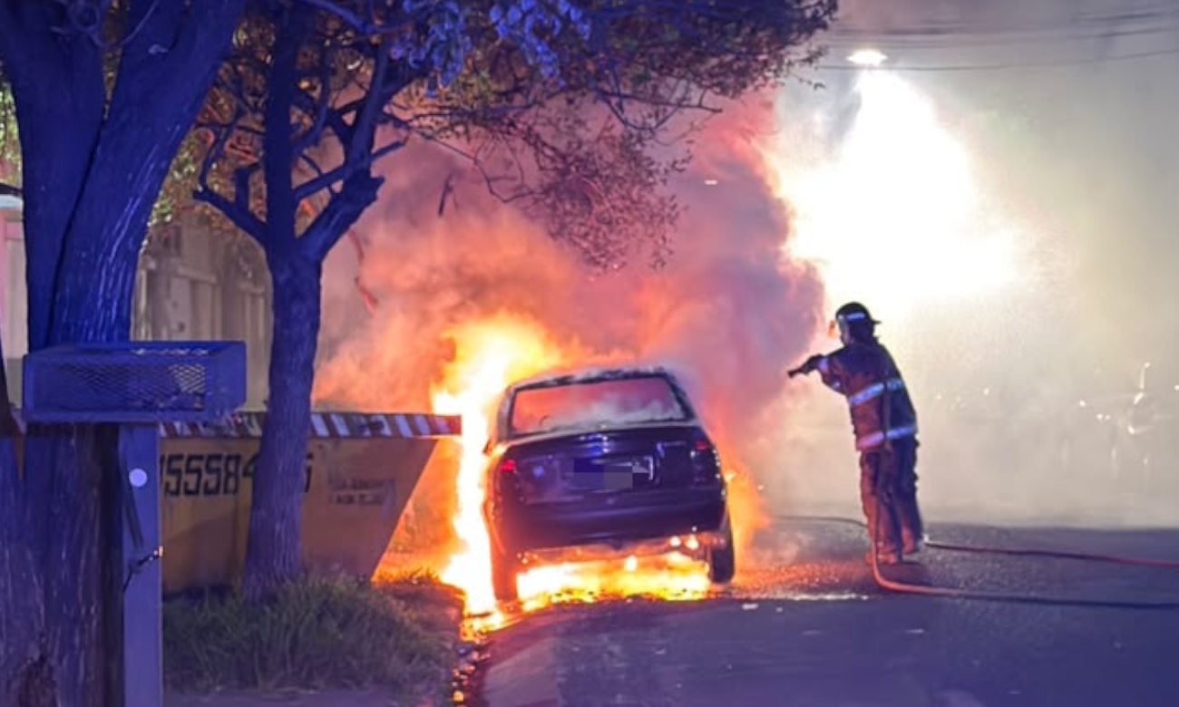 Bomberos trabajan en el lugar tras el incendio intencional de un vehículo estacionado en Barrio Sur.